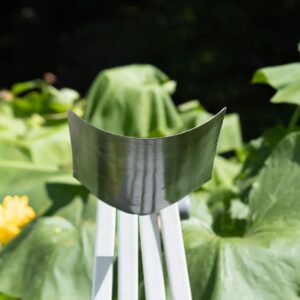 Metal sculpture with greenery background.