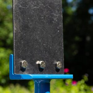 Metal signpost with bolts, outdoor background.