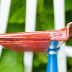 Close-up of red rake against green background.