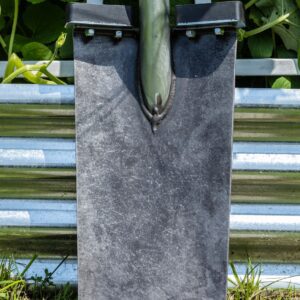 Shovel blade leaning against metal fence.