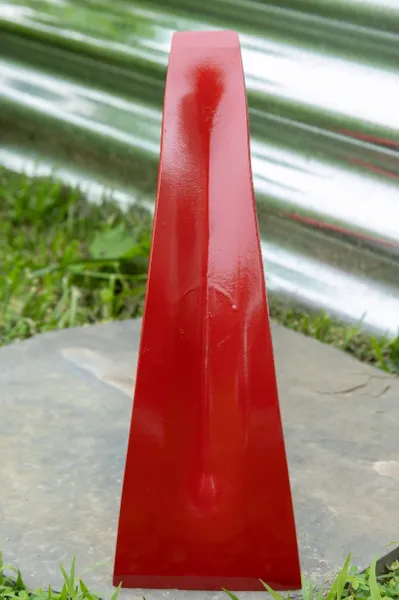 Red triangular metal wedge on stone