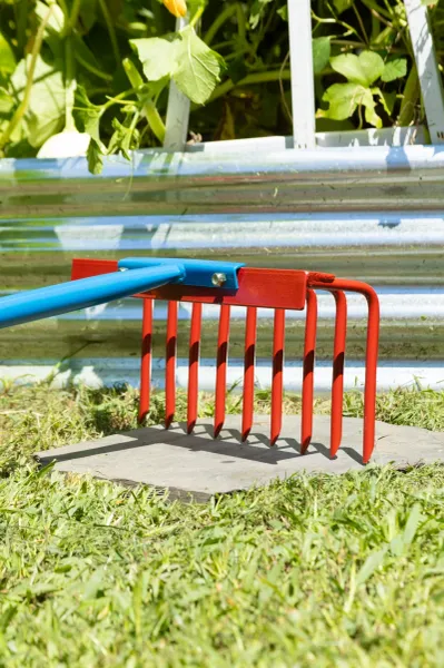 Red garden rake with blue handle on grass