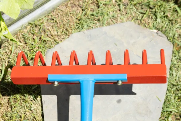 Red rake with blue handle on grass
