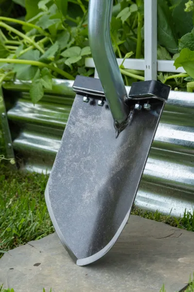 Garden shovel blade leaning against raised bed