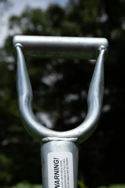 Metal D-handle shovel grip with warning label