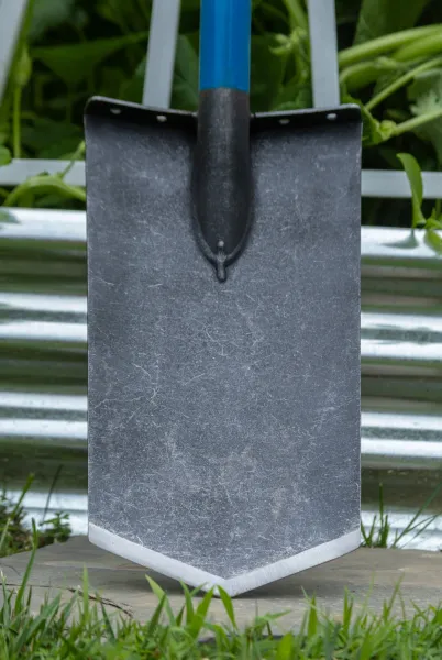 Garden shovel blade with blue handle in grass