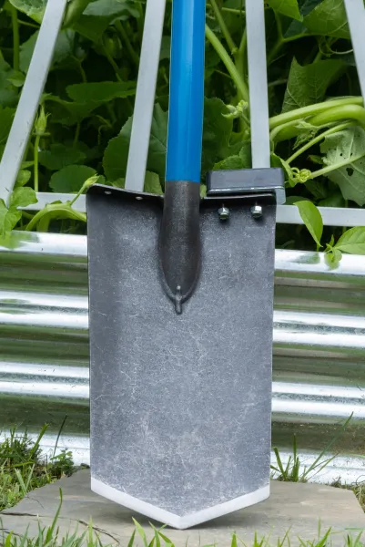 Blue-handled garden shovel leaning on metal