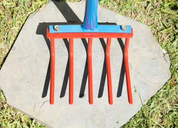 Garden rake with red tines on stone