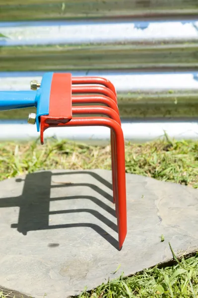 Red metal cultivator tines casting shadow