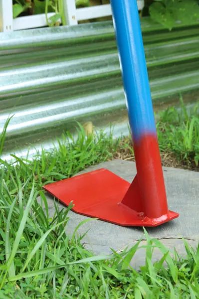 Red metal hoe with blue handle on grass
